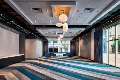 a hallway of a lobby with blue chairs and windows at Aloft Fort Worth Downtown in Fort Worth