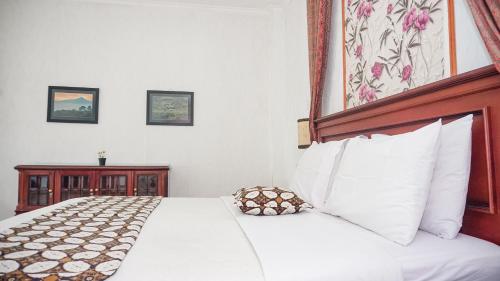 a bedroom with a bed with white sheets and pillows at Villa Venetys Lembang by BWB in Cikidang 1