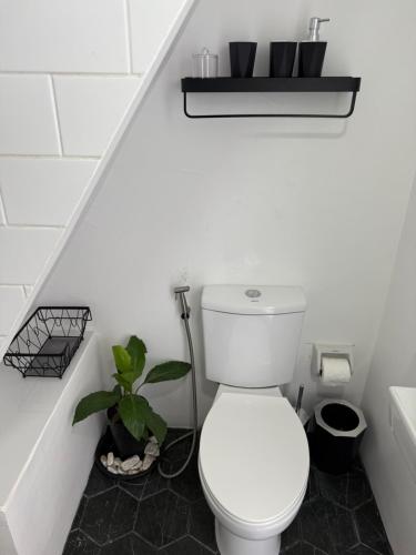 a white bathroom with a toilet and a plant at Las Villas De La Serenidad in Calatagan