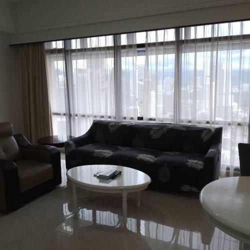 a living room with a black couch and a coffee table at Fantastic appartment at times square Kuala Lumpur in Kuala Lumpur