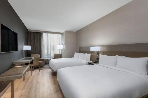 a large hotel room with two beds and a television at AC Hotel by Marriott Atlanta Midtown in Atlanta