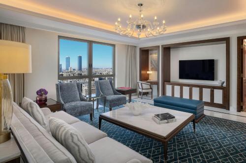 a living room with a couch and chairs and a tv at The Ritz-Carlton, Amman in Amman