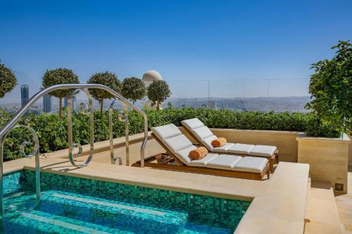 a pool with lounge chairs next to a swimming pool at The Ritz-Carlton, Amman in Amman