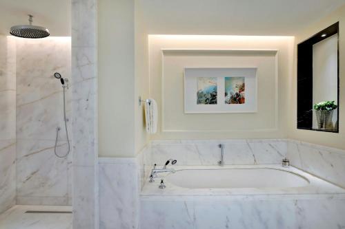 a white bathroom with a tub and a shower at The Ritz-Carlton, Amman in Amman