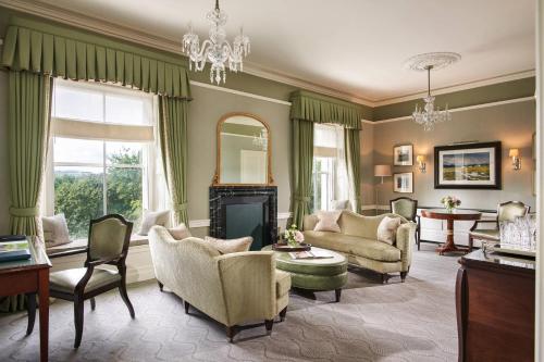 a living room with green curtains and a fireplace at The Shelbourne, Autograph Collection in Dublin