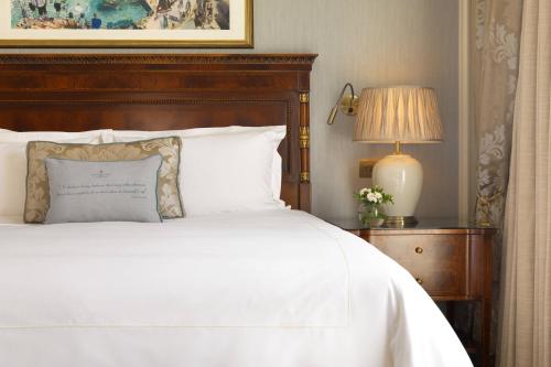 a bedroom with a white bed with a wooden headboard at The Shelbourne, Autograph Collection in Dublin