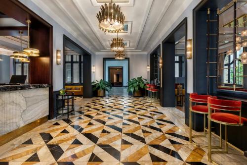 フランクフルト・アム・マインにあるLUME Boutique Hotel, Autograph Collectionのチェッカーフロアのロビーと赤い椅子