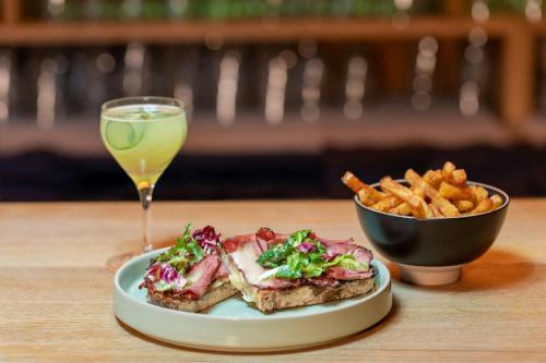 a plate of food and a bowl of fries and a drink at LUME Boutique Hotel, Autograph Collection in Frankfurt/Main