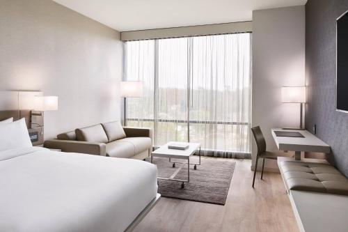 a hotel room with a bed and a couch and a desk at AC Hotel by Marriott Charlotte SouthPark in Charlotte