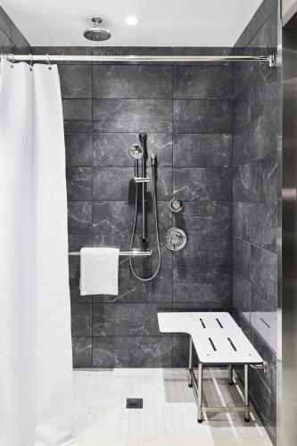 a bathroom with a shower with a bench in it at AC Hotel by Marriott Charlotte SouthPark in Charlotte