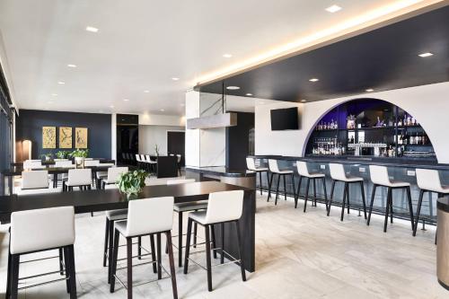 a restaurant with a bar with white stools at AC Hotel by Marriott Charlotte SouthPark in Charlotte