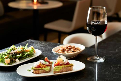 a table with two plates of food and a glass of wine at AC Hotel by Marriott Charlotte SouthPark in Charlotte