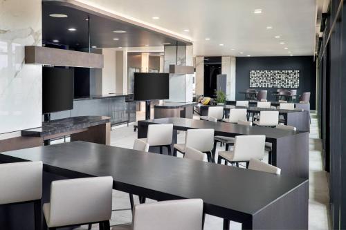 a restaurant with black tables and white chairs at AC Hotel by Marriott Charlotte SouthPark in Charlotte