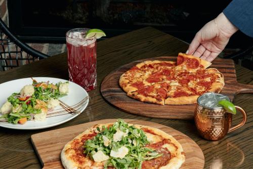 a table with two pizzas and a plate of salad at The Lytle Park Hotel, Autograph Collection in Cincinnati