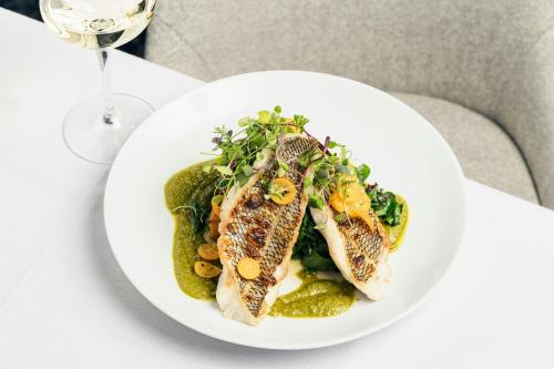 a plate of food with fish and vegetables on a table at The Lytle Park Hotel, Autograph Collection in Cincinnati