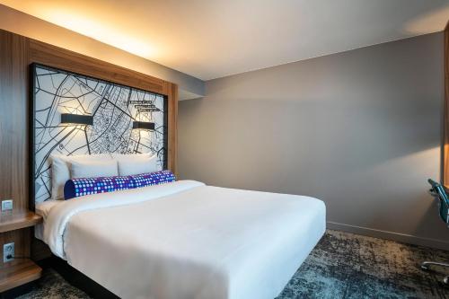 a bedroom with a large white bed and a window at Aloft Brussels Schuman in Brussels