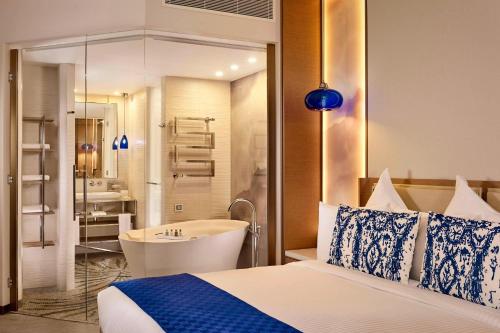 a bedroom with a bed and a tub and a sink at Paragraph Resort & Spa Shekvetili, Autograph Collection in Shekvetili