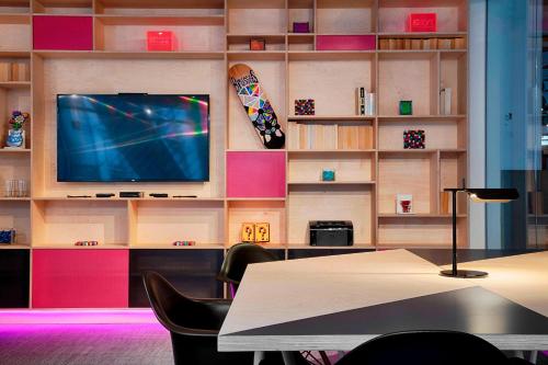a room with a tv and a table and chairs at Aloft Brussels Schuman in Brussels