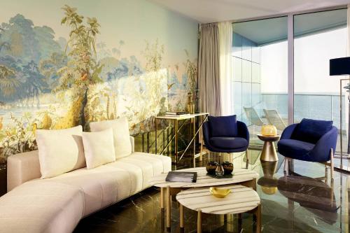 a living room with a white couch and blue chairs at Paragraph Resort & Spa Shekvetili, Autograph Collection in Shekvetili