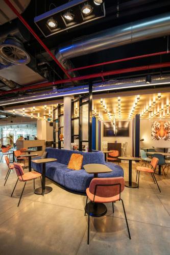 a room with a blue couch and tables and chairs at Aloft Brussels Schuman in Brussels