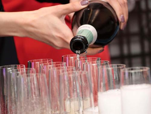 a woman pouring a bottle of wine into glasses at Kempinski Residences Guangzhou - Free shuttle between hotel and Exhibition Center during Canton Fair & Exhibitor registration Counter in Guangzhou