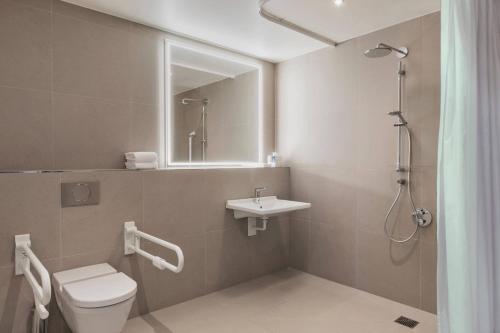 a bathroom with a toilet and a sink and a shower at Courtyard by Marriott Freiburg in Freiburg im Breisgau