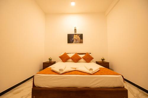 a bedroom with a large bed with orange pillows at Hotel Herb Garden in Udawalawe