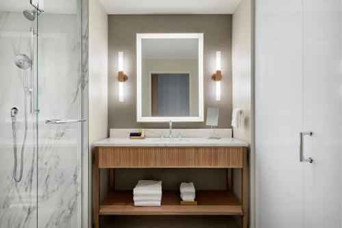 a bathroom with a sink and a mirror and a shower at HALL Park Hotel, Autograph Collection in Frisco