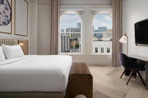 a hotel room with a bed and a desk and a window at The Union Station Nashville Yards, Autograph Collection in Nashville