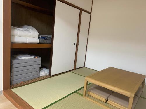 a room with a closet with a bench and a table at 軽井沢七福荘ホテル in Tsumagoi