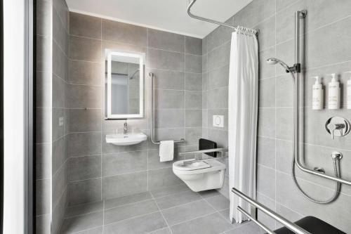 a bathroom with a toilet and a sink and a shower at Courtyard by Marriott Biel Bienne in Biel