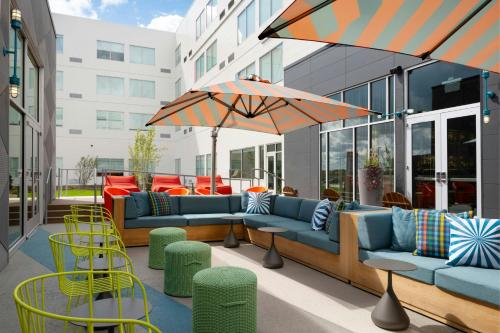a patio with couches and chairs and an umbrella at Aloft Waukee in Waukee