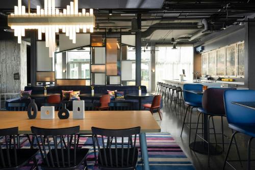 a restaurant with tables and chairs and a bar at Aloft Waukee in Waukee