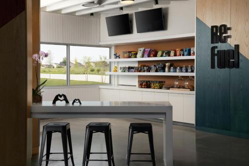 a kitchen with a table and three stools at Aloft Waukee in Waukee