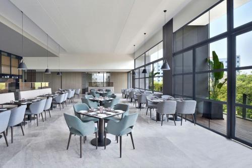 a restaurant with tables and chairs and large windows at Fairfield by Marriott Vadodara in Vadodara