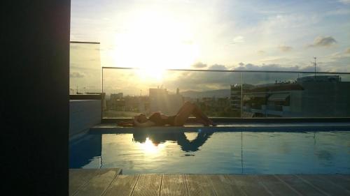 a woman laying on the edge of a swimming pool at Athina Art Apartments in Athens