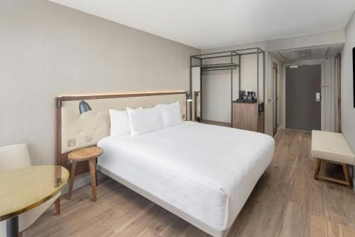 a hotel room with a large white bed and a table at AC Hotel by Marriott Glasgow in Glasgow