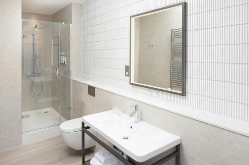 a bathroom with a sink and a toilet and a mirror at AC Hotel by Marriott Glasgow in Glasgow
