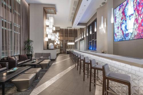a lobby with a bar with chairs and a large screen at AC Hotel by Marriott Charlotte City Center in Charlotte