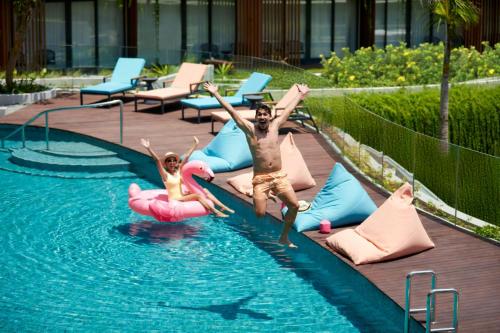 a man and a child jumping in a swimming pool at Aloft Bali Kuta at Beachwalk in Kuta