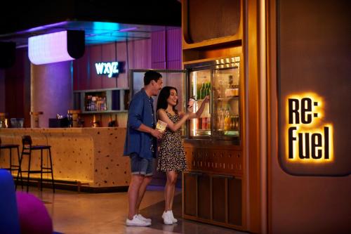 a man and a woman standing in front of a bar at Aloft Bali Kuta at Beachwalk in Kuta