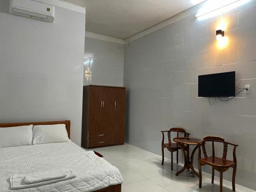 a bedroom with a bed and a table and a tv at Nhà nghĩ Tốt Hơn in Phú Quốc