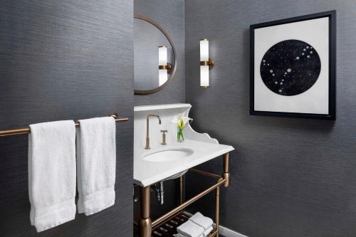 a bathroom with a sink and a mirror and towels at Hotel LeVeque, Autograph Collection in Columbus