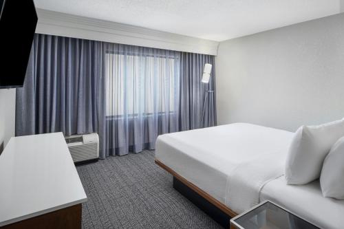 a hotel room with a bed and a window at Courtyard Baton Rouge South in Baton Rouge