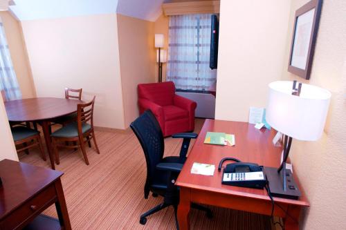 a room with a desk and a red chair and a table at Courtyard Middlebury in Middlebury