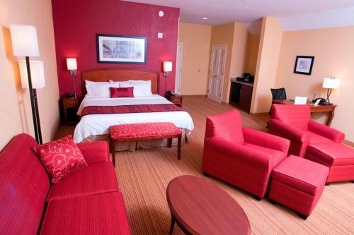 a hotel room with a bed and red furniture at Courtyard Middlebury in Middlebury