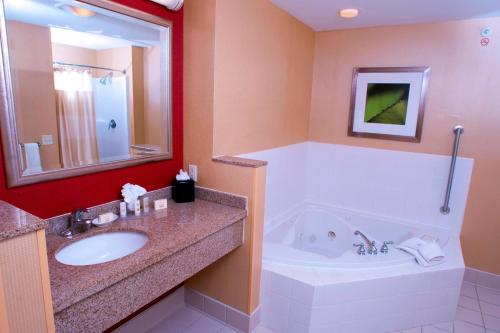 a bathroom with a tub and a sink and a bath tub at Courtyard Middlebury in Middlebury