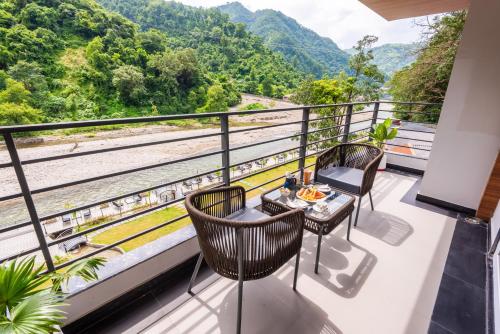 a balcony with tables and chairs and a view of a river at DLS Divine River Resort and Spa, Rishikesh in Rishīkesh