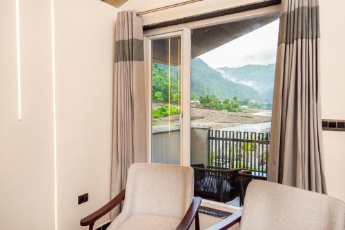 a room with two chairs and a large window at DLS Divine River Resort and Spa, Rishikesh in Rishīkesh