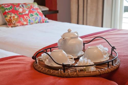 a tray with a tea pot and cups on a bed at Hotel Parque das Laranjeiras in Vilamoura